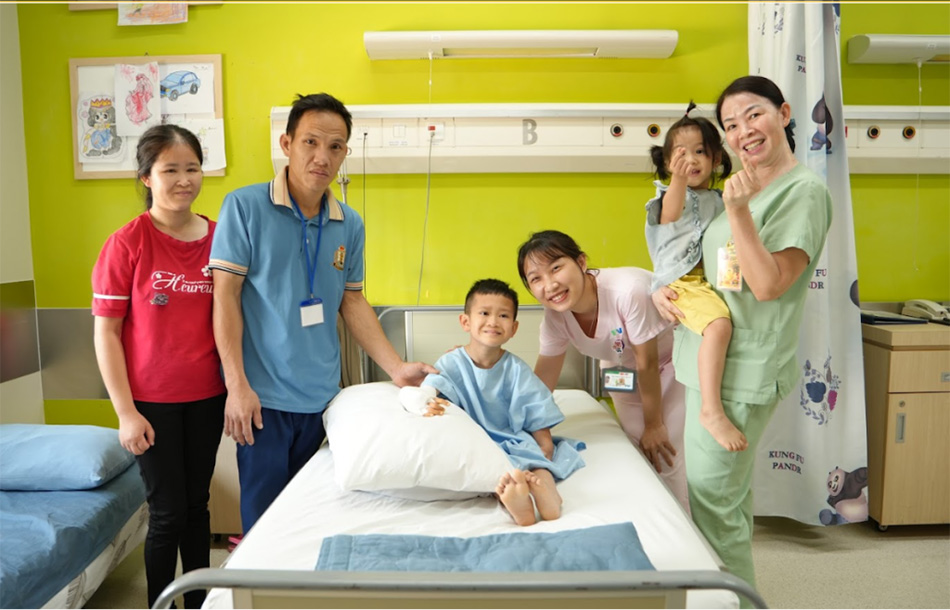 Bé Duy Quang chụp hình kỷ niệm cùng ba mẹ và các điều dưỡng của bệnh viện